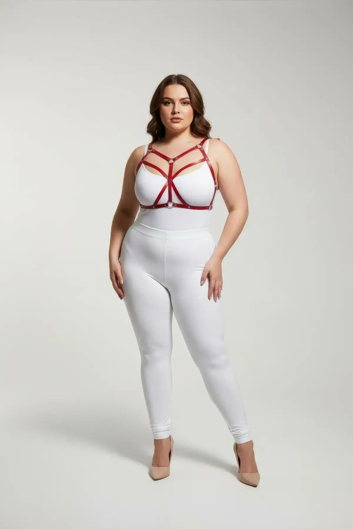 Plus-size red cross-strap faux leather harness worn by a model over a white outfit; geometric strap design.