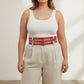 HarnessClub plus-size red double-row grommet belt with multiple buckles, vegan leather, worn at waist over a white top.