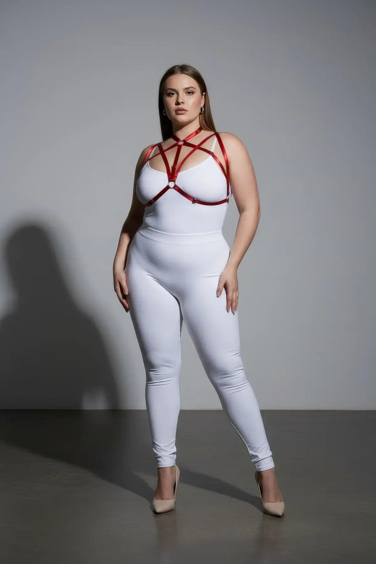 Plus-size red elastic O-ring harness set worn over a white bodysuit.