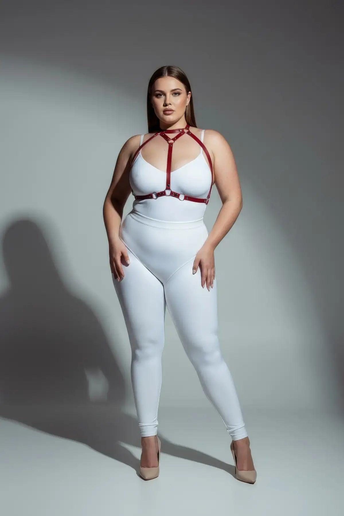 Plus-size red faux-leather body harness by HarnessClub worn over a white bodysuit.