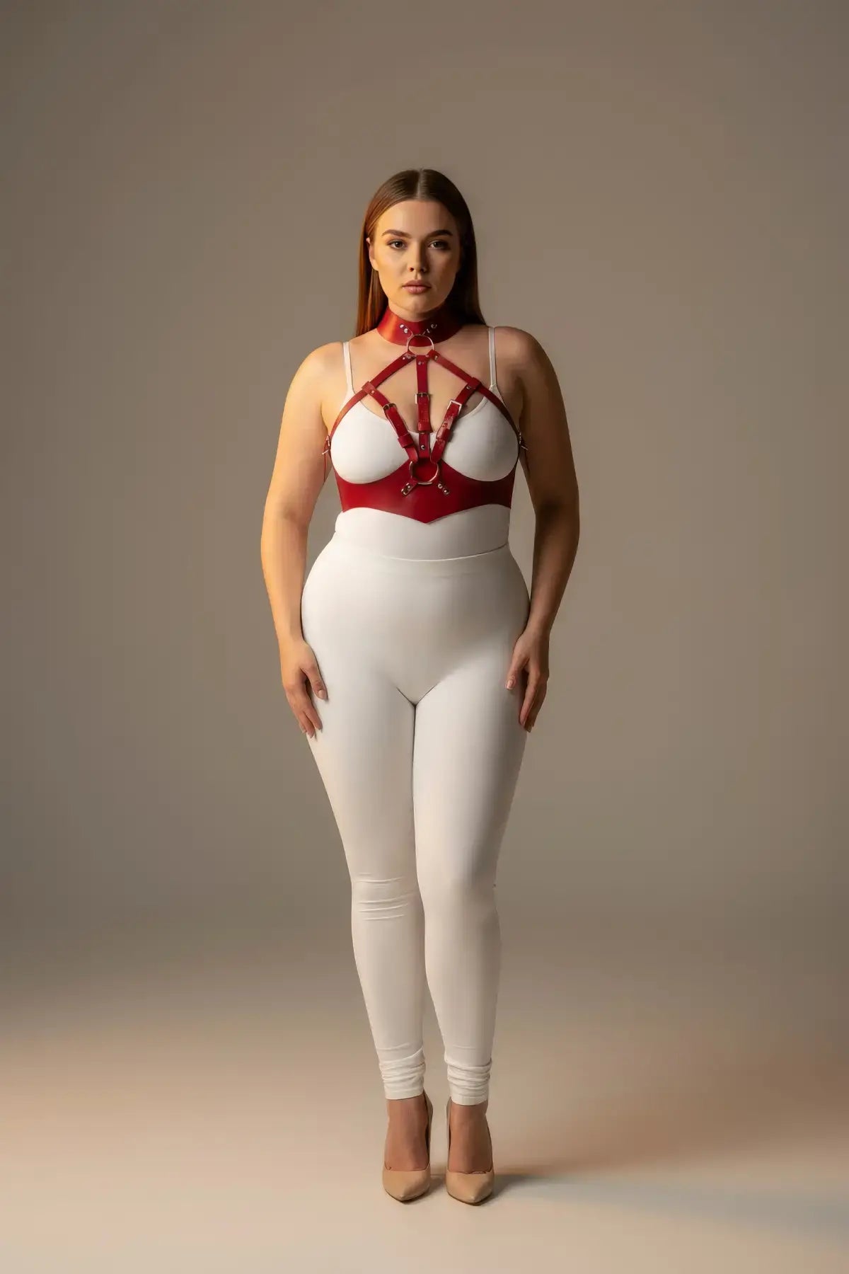Plus-size red faux-leather harness set with leash by HarnessClub, worn over a white bodysuit.