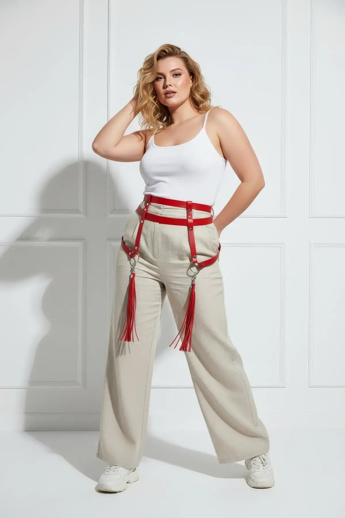 Plus-size red vegan-leather garter hip belt with leg straps and tassels worn over beige pants