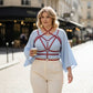 Plus-size red vegan leather geometric star cage harness worn over a light blue blouse in an urban street scene
