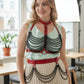 Plus-size red vegan leather harness with black chain bib, worn over light mint top