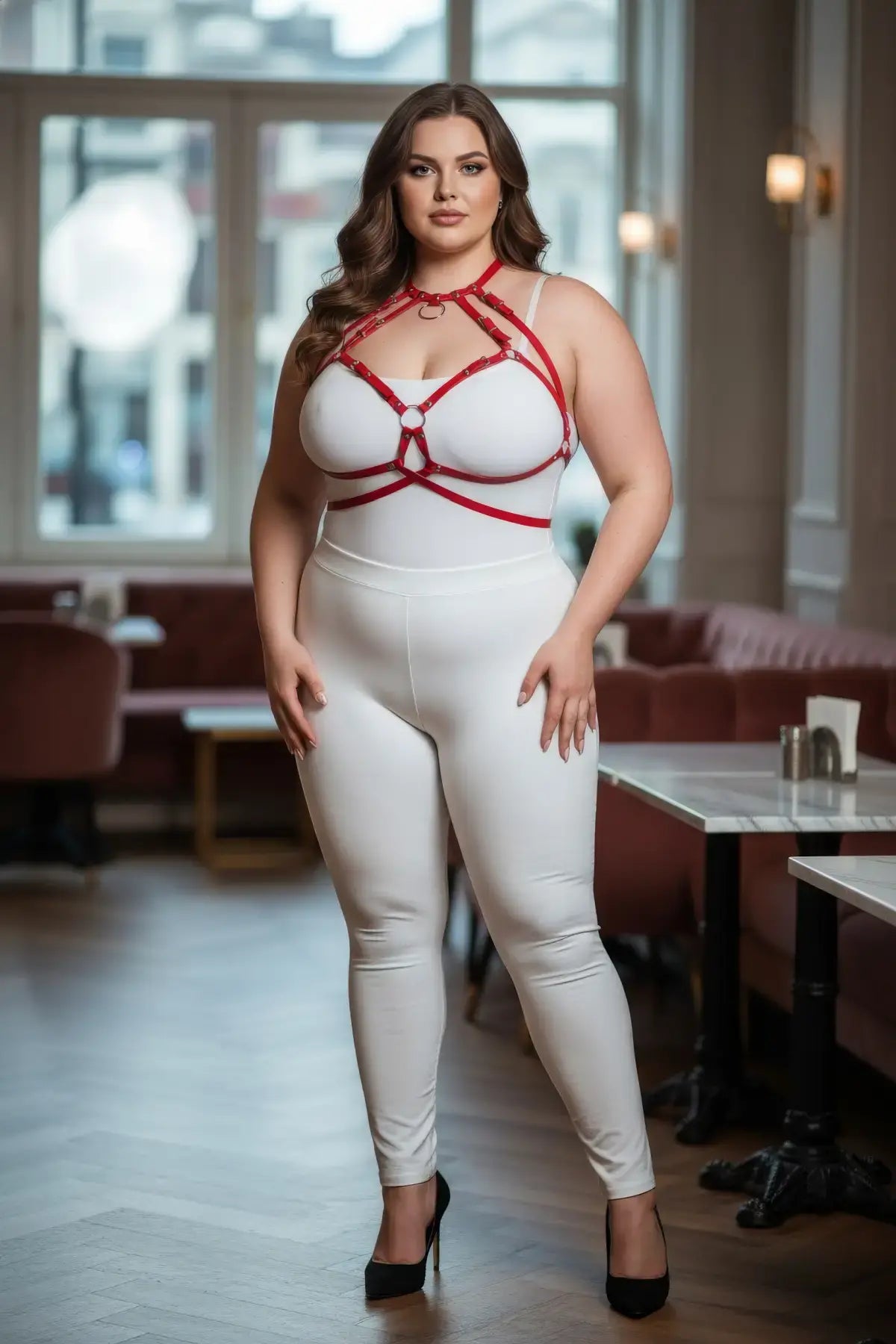 Plus-size red O-ring faux leather chest harness with strappy design worn over a white bodysuit.