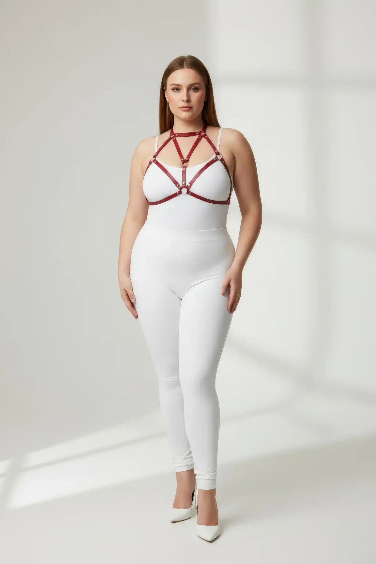 Plus-size red faux-leather O-ring body harness worn over a white bodysuit