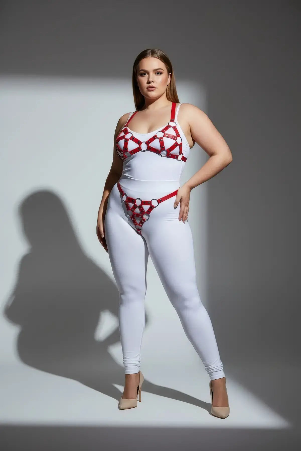 Plus-size red O-ring faux-leather body harness set by HarnessClub worn over a white bodysuit