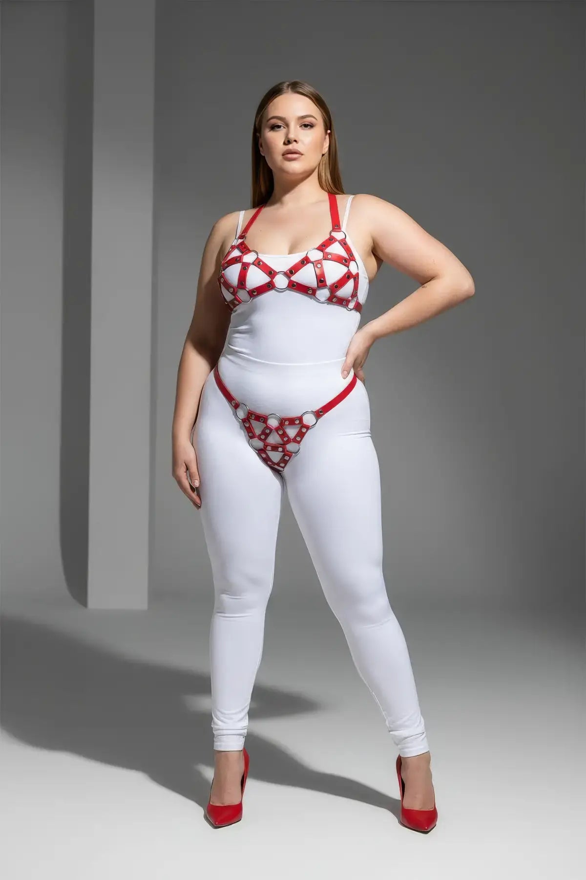 Plus-size red faux-leather O-ring body harness set worn over a white bodysuit.