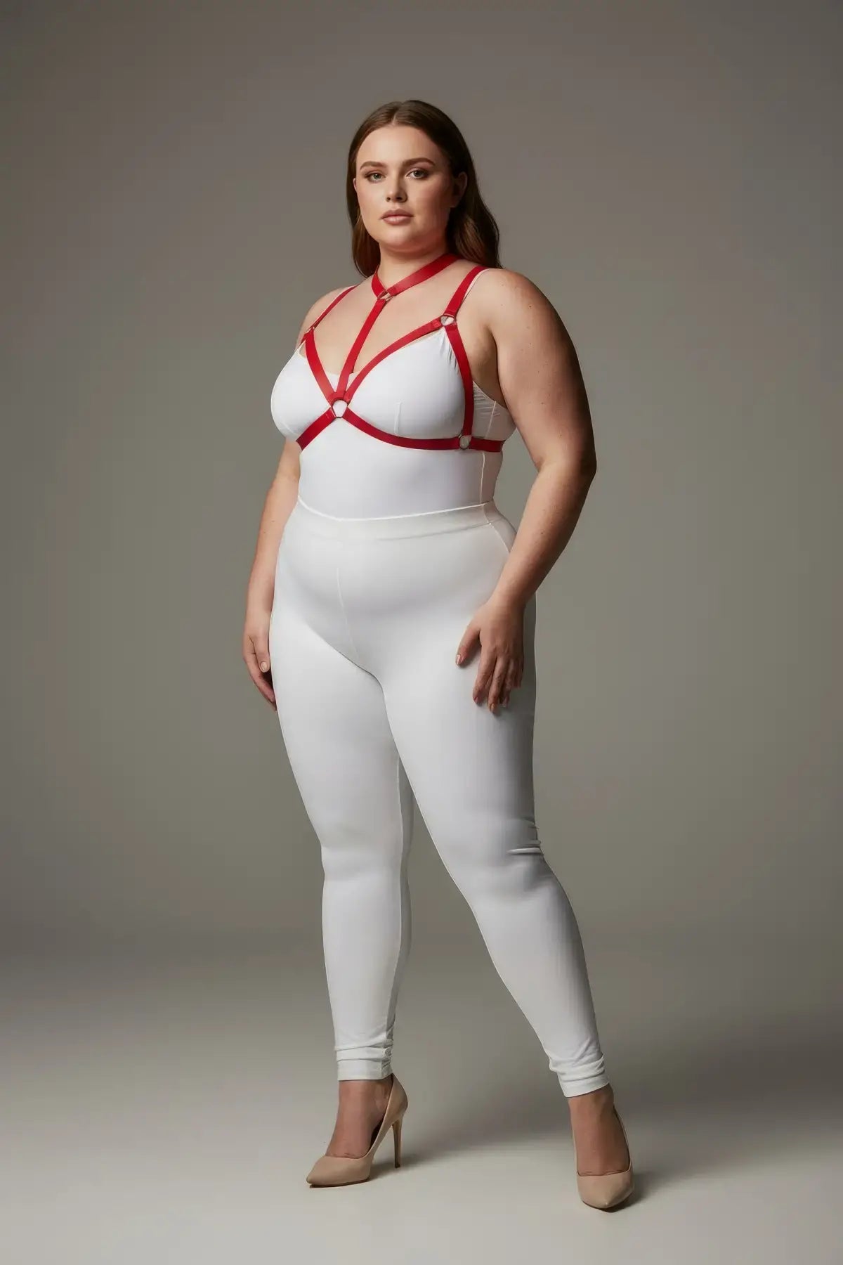 Plus-size red ring-detail elastic chest harness by HarnessClub worn over a white bodysuit.