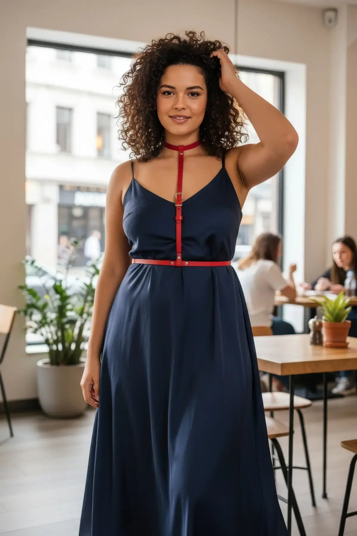 Plus size red vegan leather Y-strap harness with waist belt worn over navy dress on model.