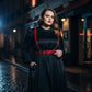 Plus size red leather garter belt with straps worn over a black dress in a nighttime city setting.