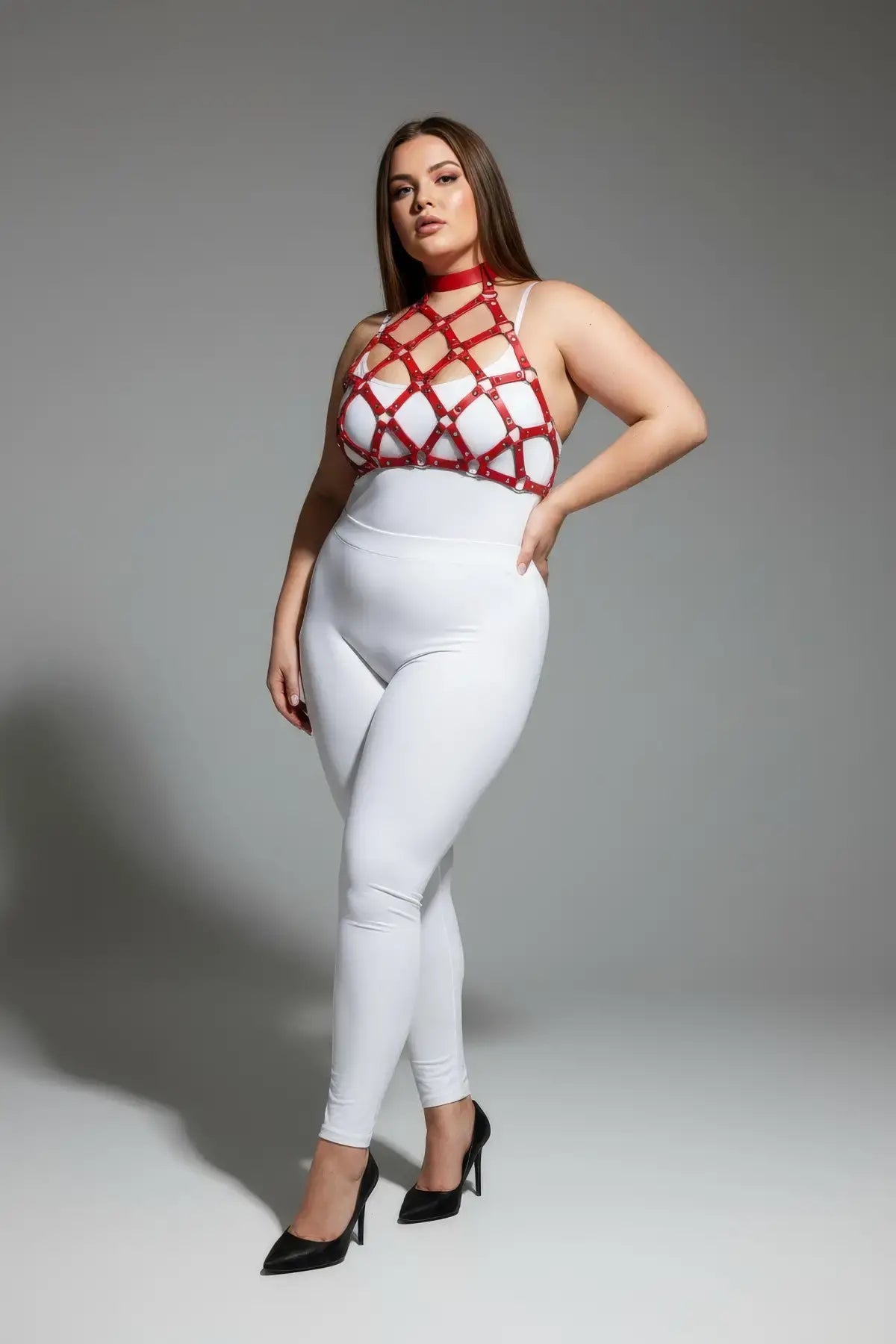 Plus-size red stud-detail faux leather chest harness worn by a model over white clothing