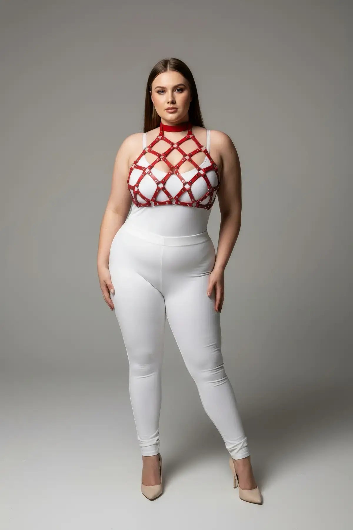 Plus-size red stud-detail faux leather chest harness by HarnessClub worn over a white top