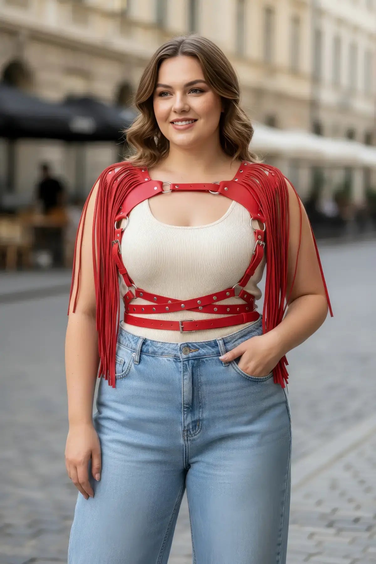 Plus-size red tasseled leather body harness on a smiling woman, featuring metal rings and buckles.