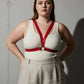 Plus-size red vegan leather V-frame chest harness with O-ring worn over a white top