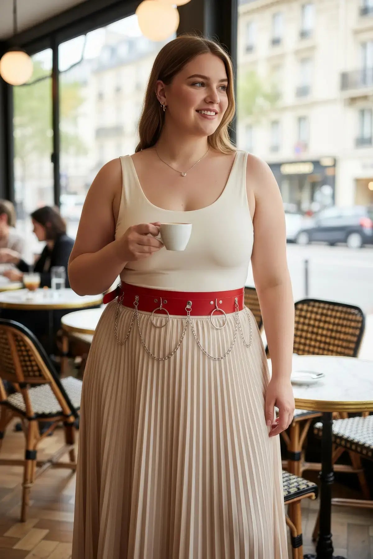 Plus-size red vegan leather waist belt with twin silver O-rings and chain detailing worn over a beige pleated skirt