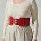 Plus size red vegan leather wide-buckle corset belt with triple buckles worn over a beige outfit for waist cinching