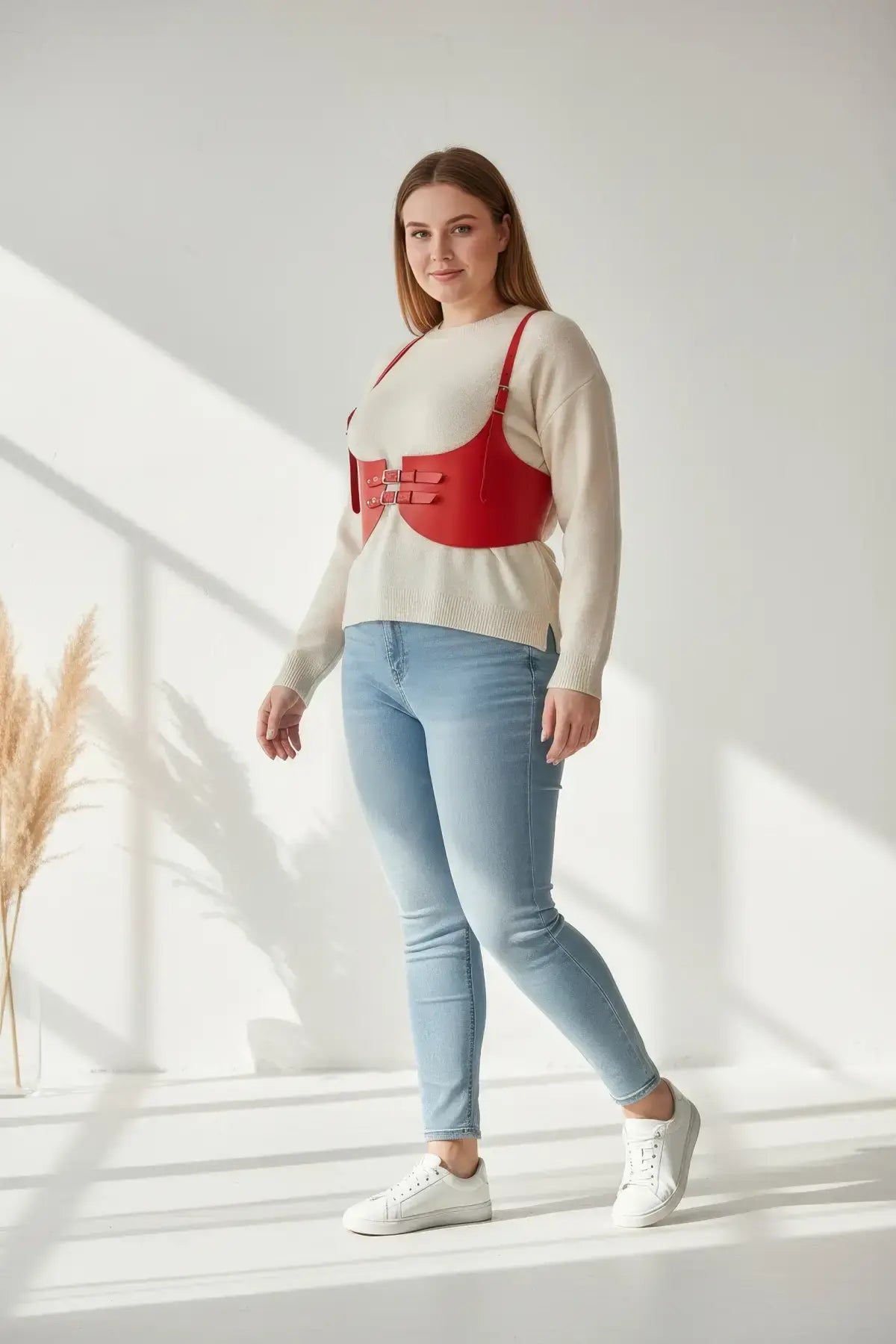 Plus-size red wide corset belt harness in vegan leather worn as an under-bust waist piece over a cream sweater