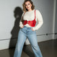 Plus Size Red Wide Corset Belt Harness in vegan leather, worn at the waist over a cream knit sweater.