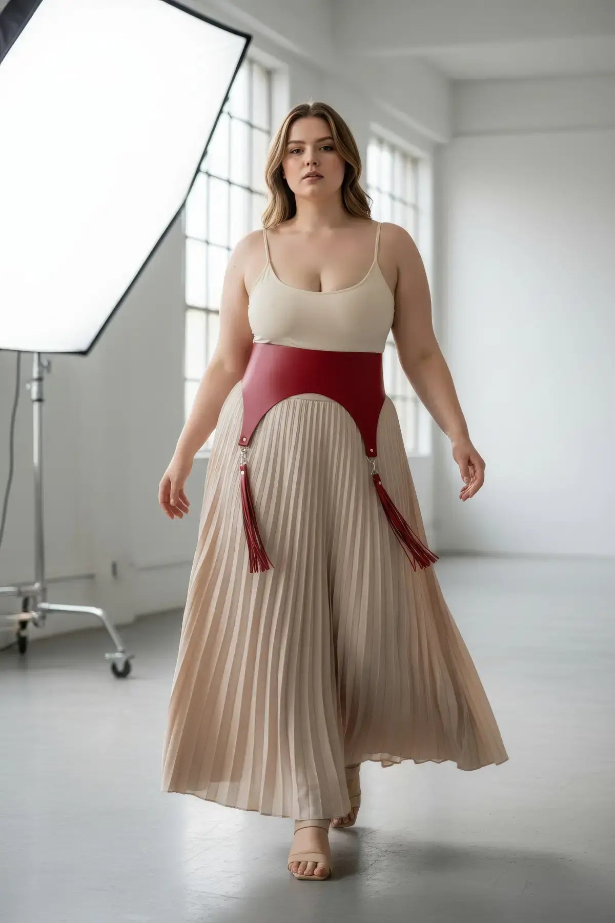 Plus size red vegan leather corset waist belt with tassels worn by a model in a studio