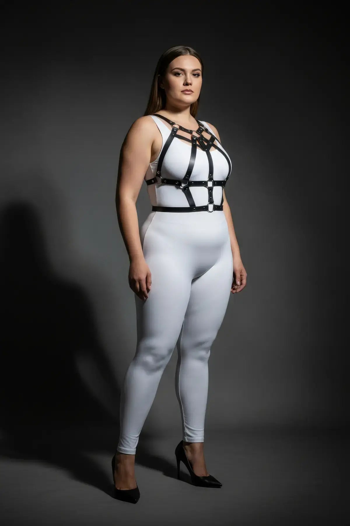 Plus-size studded strap cage chest harness by HarnessClub in vegan leather, worn over a white bodysuit