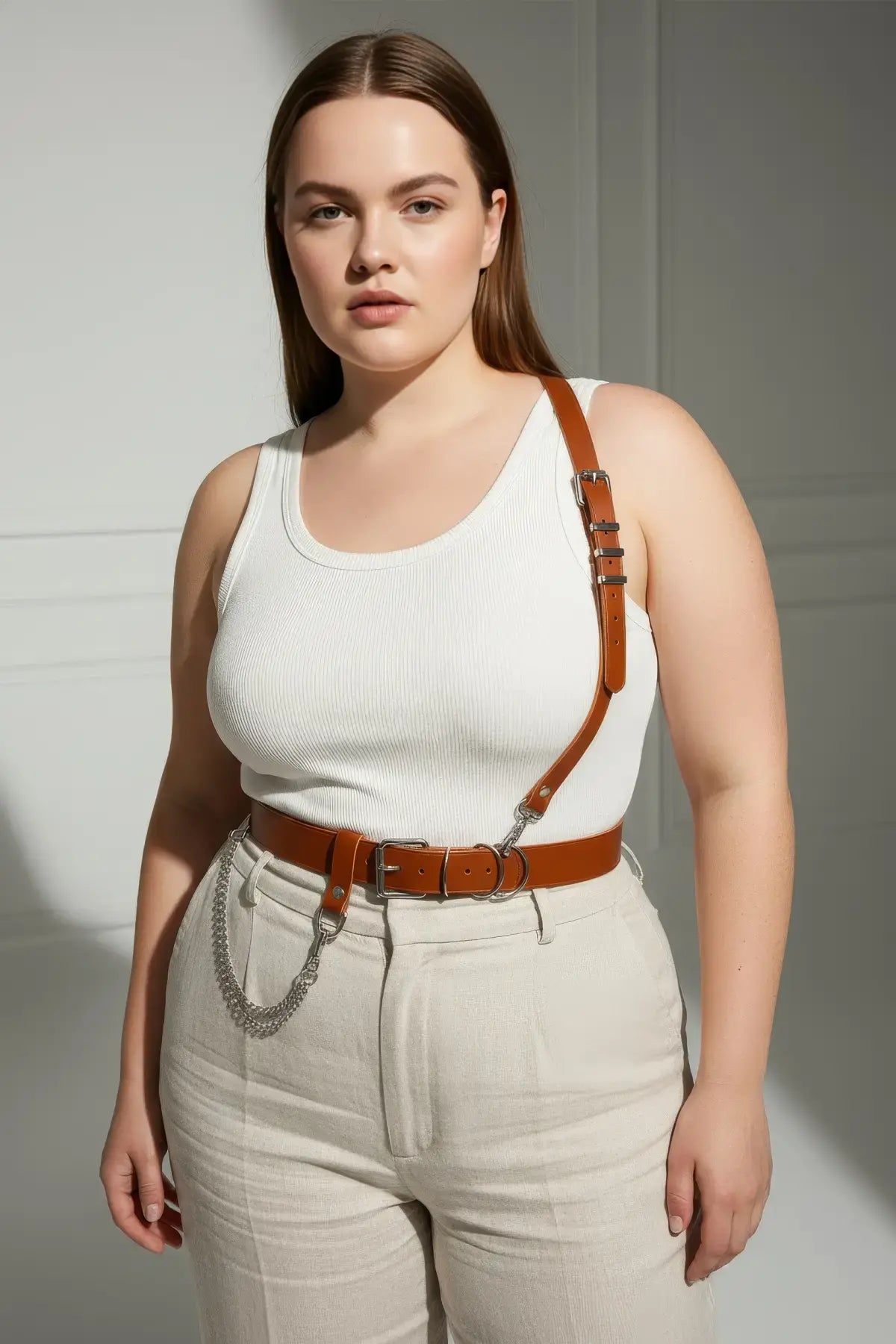 Plus-size tan genuine leather shoulder strap harness belt with chain detail worn over white tank top