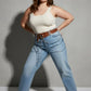 Plus-size HarnessClub tan vegan leather grommet belt with O-ring and chain detail worn at waist over jeans