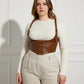 Plus-size tan vegan leather lace-up corset harness with shoulder straps worn over a white ribbed sweater