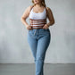 Plus-size tan vegan-leather multi-strap suspender corset harness with chain detail, worn over a tank top and jeans