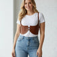 Plus-size tan vegan-leather under-bust corset harness with shoulder straps worn over a white tee