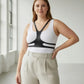 Plus size black vegan leather body harness belt worn over a white tank top with a Y-shaped chest strap.