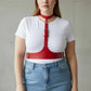 Plus-size red vegan leather corset harness worn over a white T-shirt with a wide waist belt.