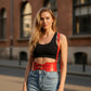 Red buckle waist cincher belt with straps, vegan leather corset belt worn over a black crop top