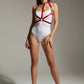 Women's red vegan-leather chest harness with silver chains worn over a white bodysuit