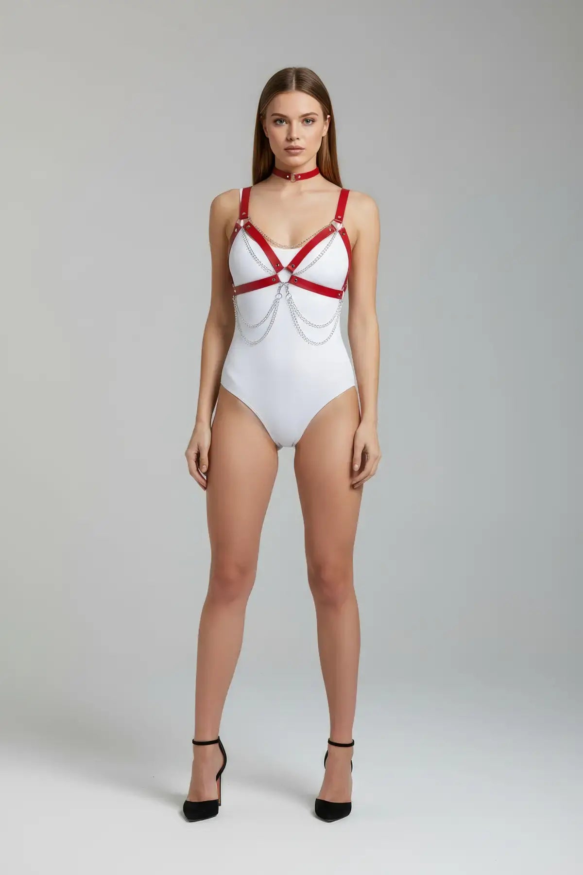 Kırmızı HarnessClub çapraz bağlamalı zincirli vücut kemeri, beyaz bodysuit üzerinde modelde.