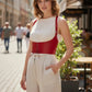 Red lace-up underbust corset belt with straps in vegan leather, worn over a white top.