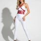 Red multi-band body harness by HarnessClub worn over a white bodysuit; vegan leather chest and waist accessory.