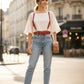 Red shoulder-strap waist harness by HarnessClub in vegan leather, worn over a white top