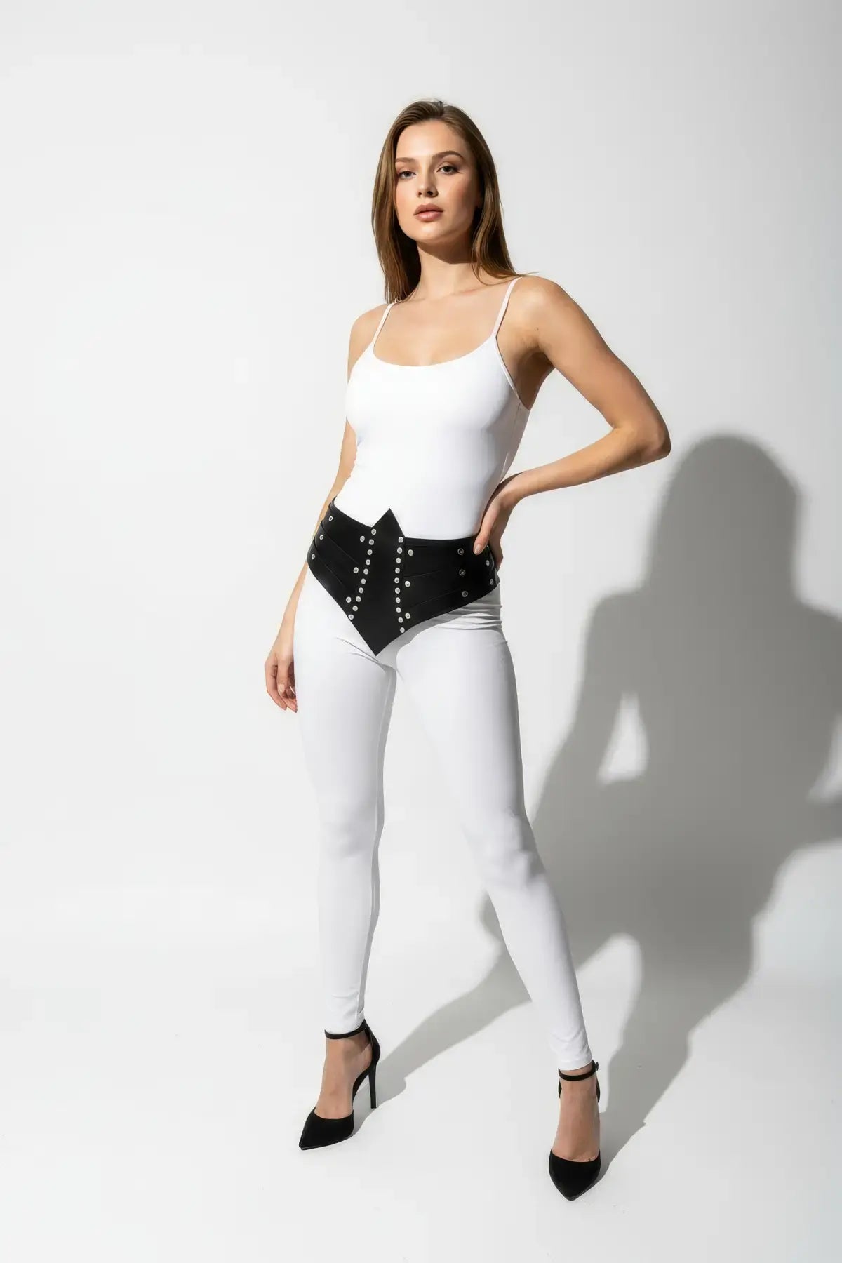 Womens black studded corset belt worn at the waist; vegan leather with silver rivet detailing.
