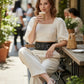 Women's black wide D-ring waist belt in vegan leather with dual metal D-rings, worn over a white outfit.