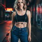 Women's clear vinyl body belt with stud detailing and metal rings, worn over a black crop top and jeans
