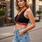 Women's red chain waist belt harness in vegan leather with metal rings, worn over a black top.