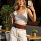 Women's tan wide double-buckle vegan leather waist belt worn over a white lace outfit.
